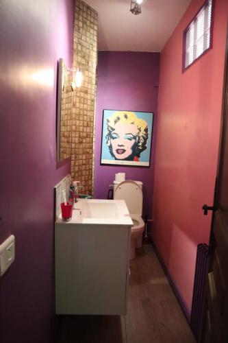 La salle de bains est pourvue de murs violets, d'un lavabo et de toilettes. dans l'établissement Belle vue mer, à Cannes