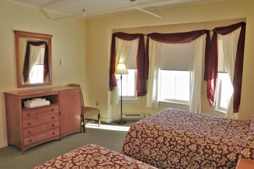 a bedroom with two beds and a dresser and a mirror at Silver Bay YMCA Inn and Conference Center in Silver Bay