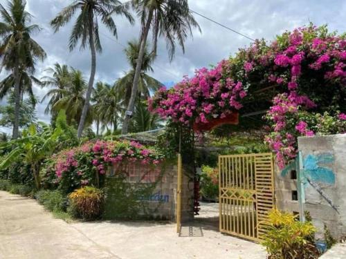 a garden with pink flowers and a wooden gate at Blue coconut villa in Kon Rung (1)