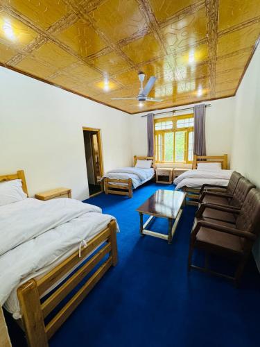 a room with two beds and a table in it at Fatah Kin Guest House in Skardu