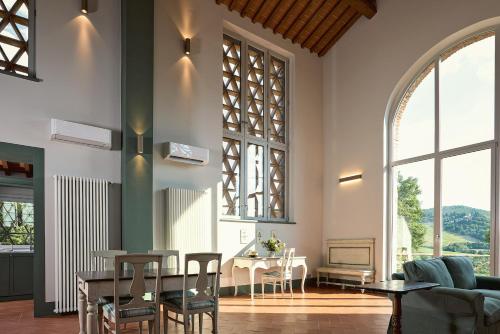 a living room with a table and chairs and windows at Castello Vicchiomaggio in Greve in Chianti