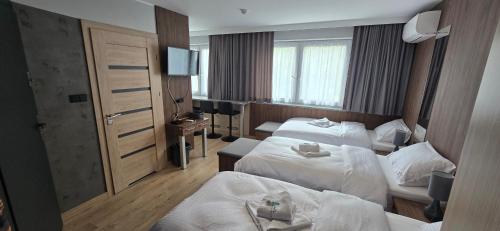 a hotel room with two beds and a television at Metropolis Apartamenty Centrum in Kalisz