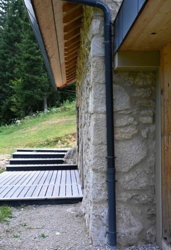 a stone building with a wooden porch and stairs at La loge de la Dolarde in Prémanon