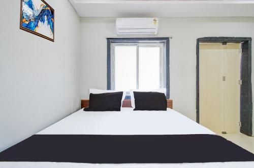 a bedroom with a large white bed with a window at Hotel O SSR Grand in Surūrnagar
