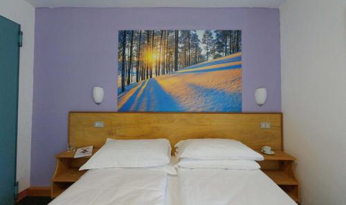 a bedroom with a bed with a painting on the wall at Hotel Teola in Livigno
