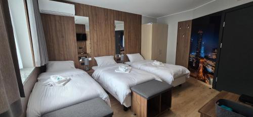 a hotel room with two beds and a chair at Metropolis Apartamenty Centrum in Kalisz