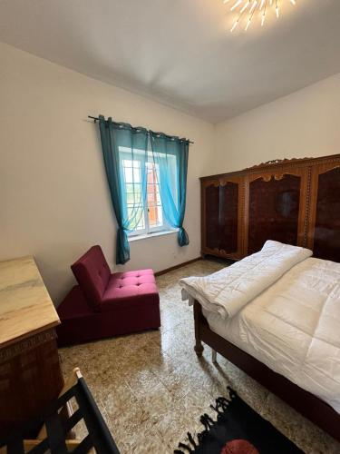 a bedroom with a bed and a chair and a window at Appartamento Tenuta Mattei in Vergato