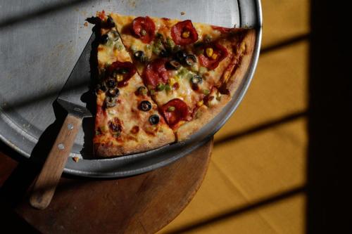 a slice of pizza on a pan on a table at Pizzeria Colisseo B & B in Jinotepe
