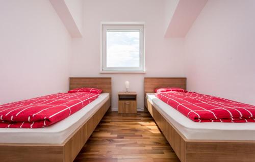 two beds in a room with red sheets and a window at Nives in Šilo