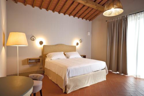 a bedroom with a white bed and a table and a table sidx sidx at Castello Vicchiomaggio in Greve in Chianti