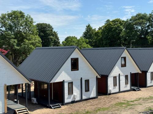 a row of white barns with black roofs at Amber Coast domek nr 2 in Jantar