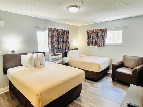 a hotel room with two beds and a chair at Tampa Bay Extended Stay - Airport in Tampa