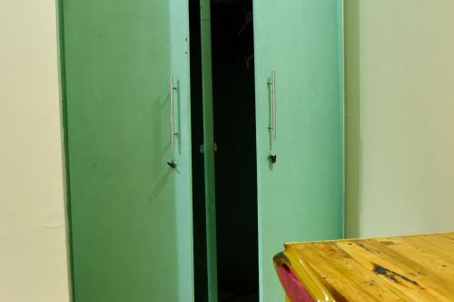 two green doors in a room with a table at L&J Modern Backpackers Kinondoni in Dar es Salaam
