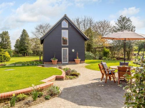 a small house with a patio and an umbrella at Granary Barn - Ukc5405 in Banham