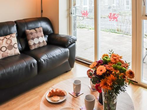 a living room with a leather couch and a table with flowers at Berwyn - Uk48507 in Bala