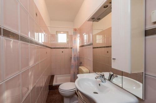 a white bathroom with a sink and a toilet at Apartments Delfin with seaview 100 meters from the sea - by TA Leut Agency in Privlaka