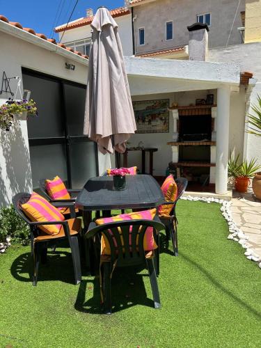 a patio with a table and chairs and an umbrella at Casa Ana in Nazaré