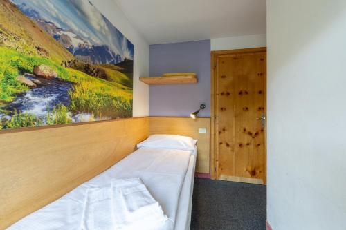 a bed in a room with a painting on the wall at Hotel Teola in Livigno