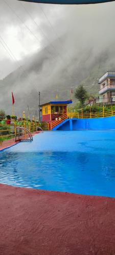 a large blue swimming pool with a building in the background at The Kempty Pool Retreat in Mussoorie