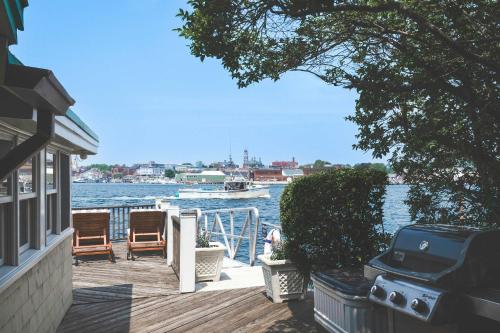 a dock with two chairs and a boat in the water at Stay at Rocky Neck in Gloucester