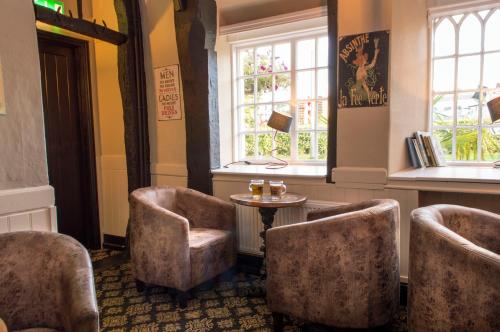a waiting room with chairs and a table and windows at The Bell Inn in Newmarket
