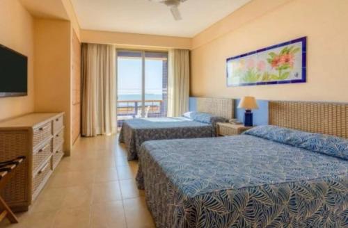 a hotel room with two beds and a television at Zuana Beach Resort in Santa Marta