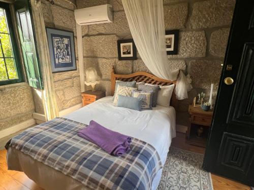a bedroom with a bed and a stone wall at Casa da Costinha in Cinfães
