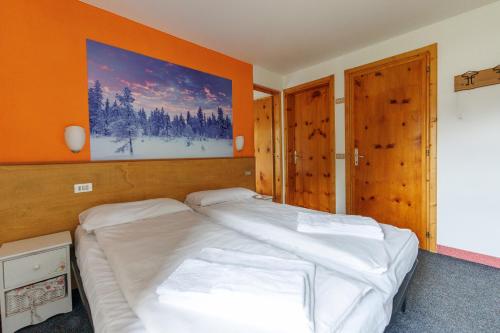a bedroom with a large white bed with an orange wall at Hotel Teola in Livigno