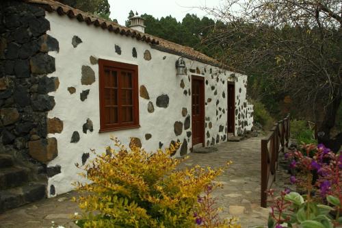 a white building with brown doors and flowers at Casa Rural el Riachuelo in Garafía