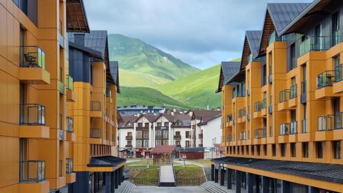 a row of buildings with mountains in the background at New Gudauri Four Seasons F3 by Gudauri Travel in Gudauri