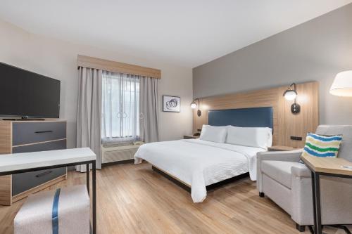 ザ・ウッドランズにあるCandlewood Suites Houston The Woodlands by IHGのベッドとテレビがあるホテルの部屋