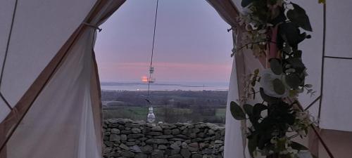 a view of a sunset from a room with a window at Fairy Hill at Rosemount Glamping in Carlingford