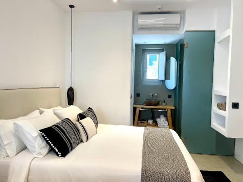 a bedroom with a white bed with black and white pillows at Mykonos Dot Suites in Ano Mera