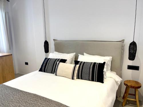 a bedroom with a white bed with black and white pillows at Mykonos Dot Suites in Ano Mera