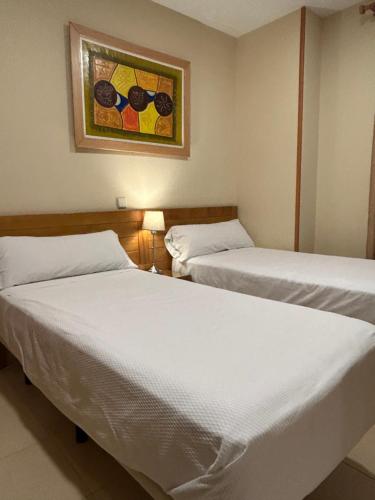 two beds in a room with a painting on the wall at Hostal Aeropuerto in Madrid