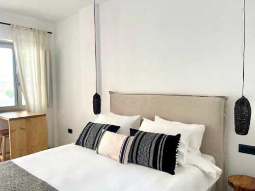 a bedroom with a white bed with black and white pillows at Mykonos Dot Suites in Ano Mera