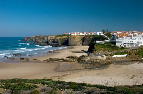 a view of a beach with houses and the ocean at big apartment in the beach in Zambujeira do Mar