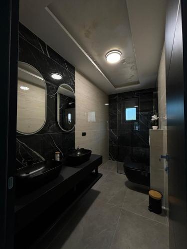 a black bathroom with two sinks and a toilet at Villa Aurea in Bihać