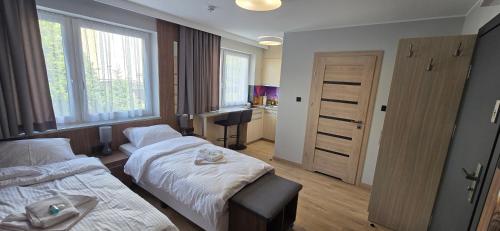 a hotel room with two beds and a door at Metropolis Apartamenty Centrum in Kalisz