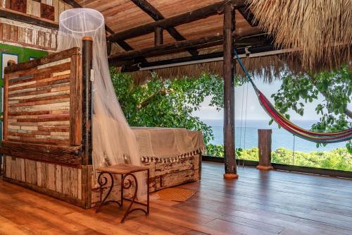 a hammock in a room with a view of the ocean at Casa El Paraiso, Eco Lodge in Santa Bárbara de Samaná