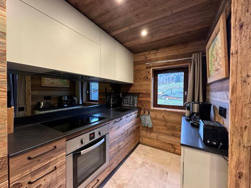une cuisine avec des armoires en bois et un four à plaques de cuisson dans l'établissement Duplex rénové 6p au pied des pistes, expo sud, balcon et wifi à Morillon - FR-1-642-56, à Morillon
