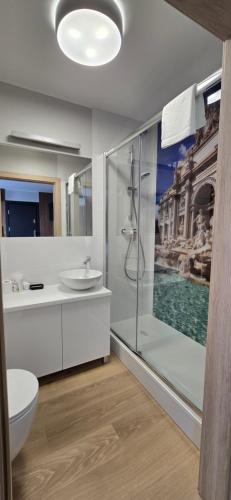 a bathroom with a shower and a toilet and a sink at Metropolis Apartamenty Centrum in Kalisz