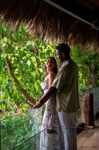 a man and a woman standing under a thatch roof at Casa El Paraiso, Eco Lodge in Santa Bárbara de Samaná