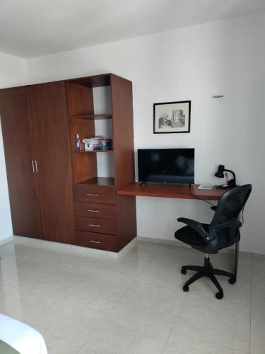 a room with a desk with a chair and a television at Casa Laak Fabulous rustic townhouse in Mérida