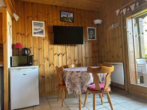 une cuisine avec une table et une télévision sur un mur en bois dans l'établissement Duplex charmant au cœur de Morillon, près lac et navette, 5 pers, balcon, équipement complet - FR-1-642-99, à Morillon