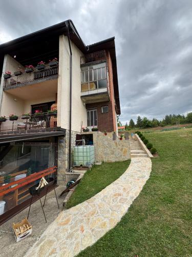 a house with a stone walkway in front of it at Vila Trtović in Nova Varoš