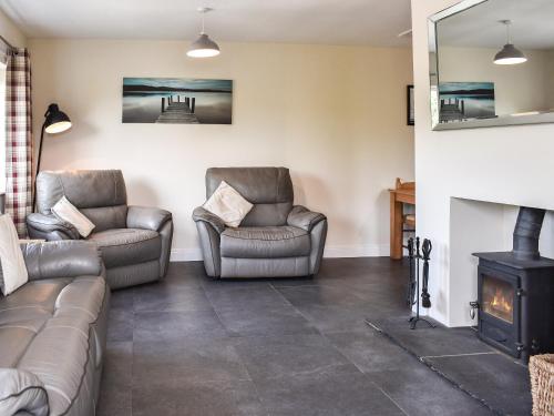 a living room with two chairs and a fireplace at Rosedean in Ireby