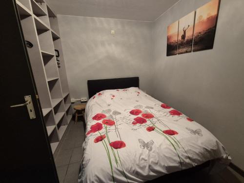 a bedroom with a bed with red flowers on it at Maison Bonne Humeur Achouffe in Houffalize