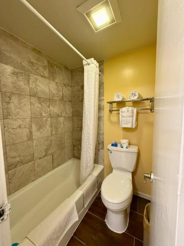 a bathroom with a white toilet and a bath tub at Monterey Bay Lodge in Monterey