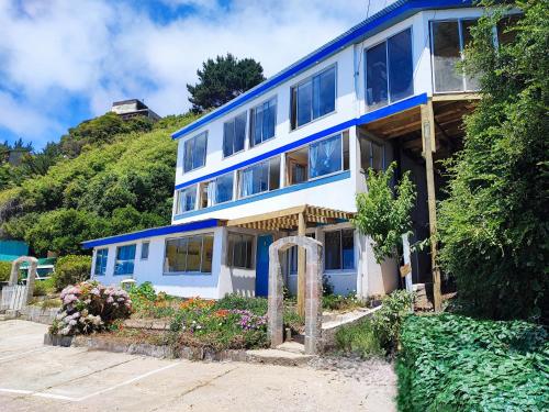 a blue and white house with flowers in front of it at Cabañas Vuelo de Gaviotas in Curanipe